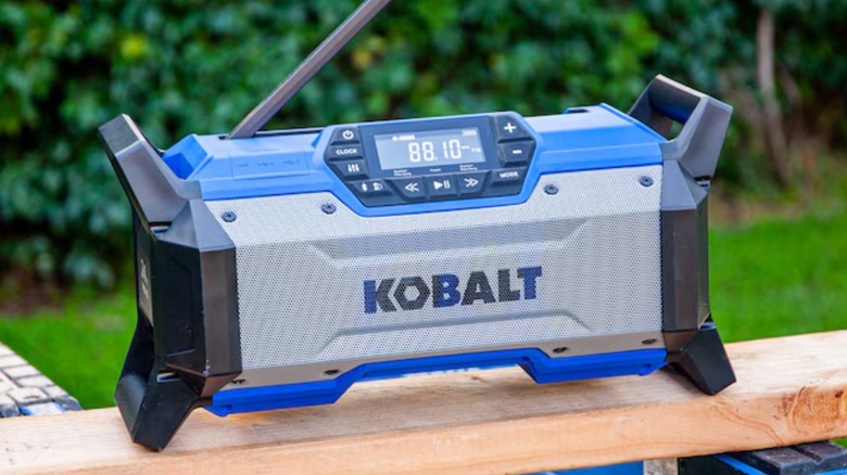 A Kobalt Bluetooth Jobsite Radio set outside on a wood railing