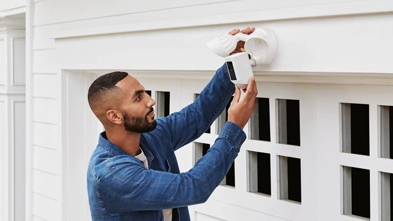 A man installing a Ring Floodlight Cam above his garage