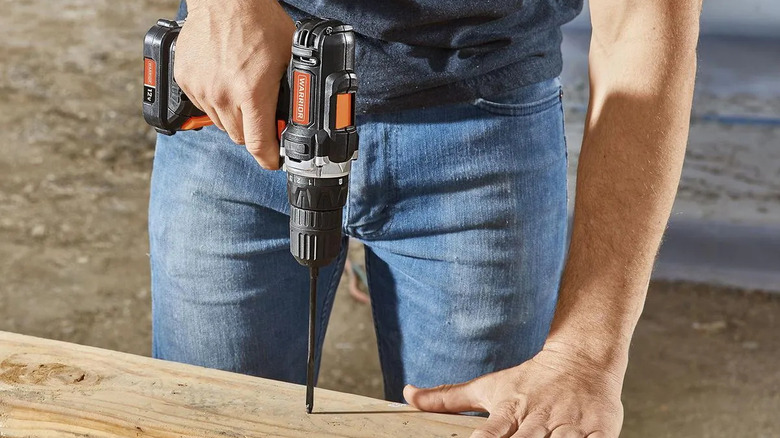 A person uses a Warrior cordless power drill from Harbor Freight.