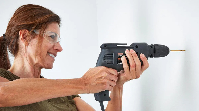 A woman uses a Warrior variable-speed drill from Harbor Freight.