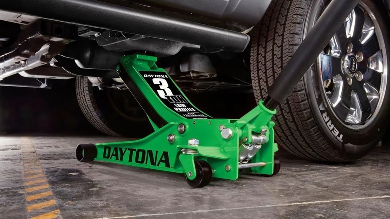 A green Daytona jack lifting a car in a garage
