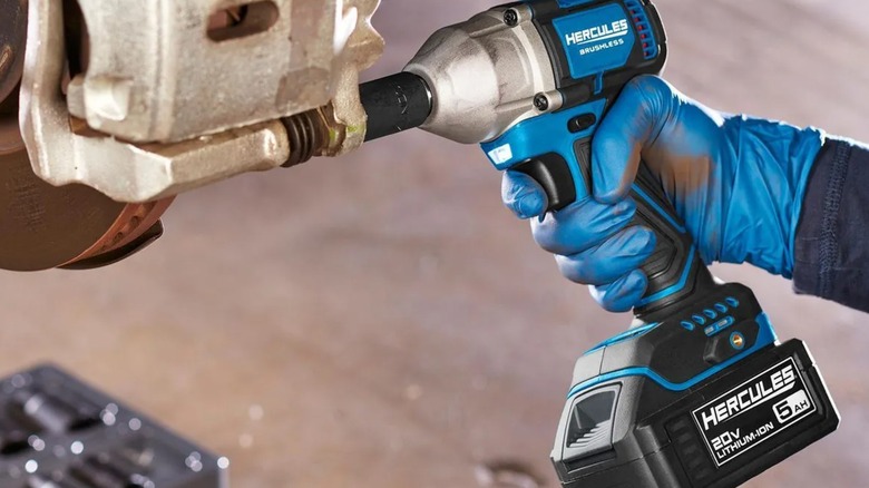 A worker wearing blue gloves using s Hercules impact wrench