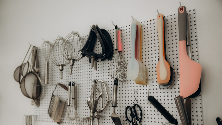 A variety of kitchen utensils hanging on a pegboard