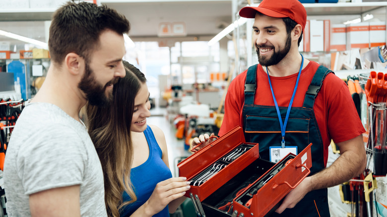Hardware store employee shows couple toolbox of tools in store.
