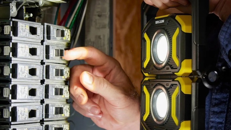 Close-up of a person using a Braun light to illuminate circuit breakers