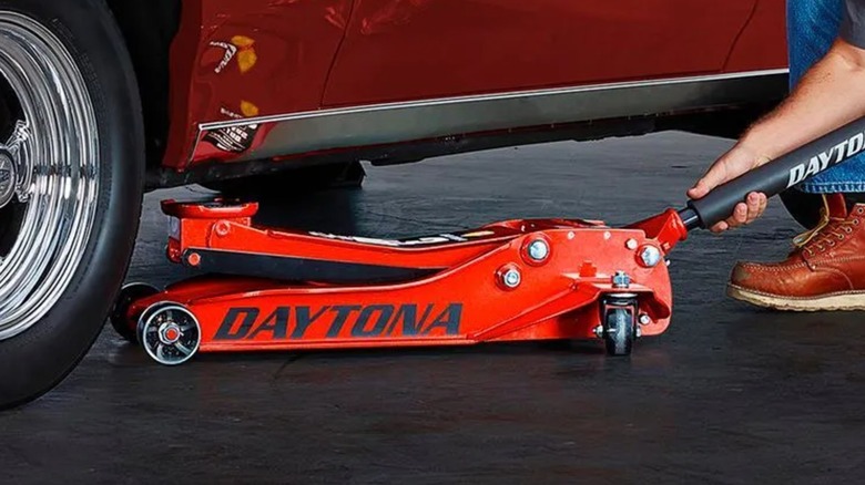 A red Daytona jack underneath a car.