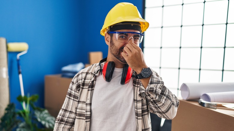 Construction worker covering nose after smelling something bad