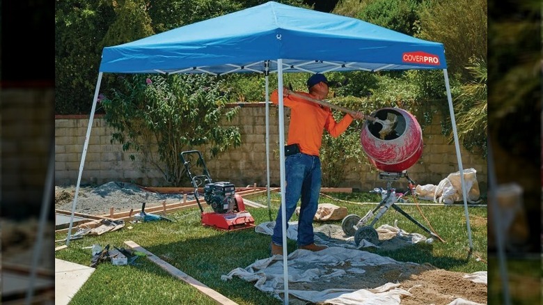 Man standing under an open-air blue-top canopy