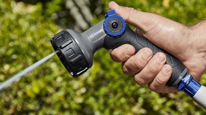 Hand using a hose spraying nozzle