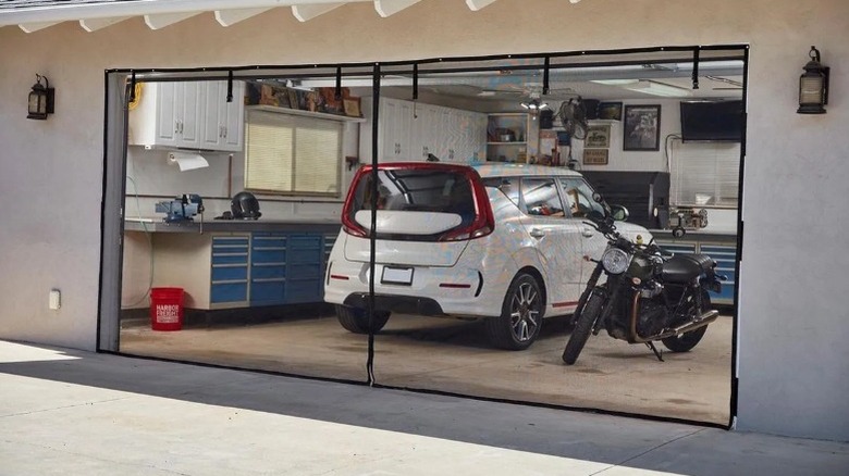 White car parked in a garage covered by a clear screen