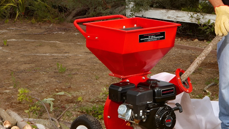 A person using the Predator wood chipper on branch