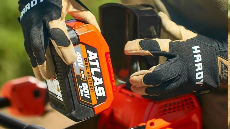 Person loading a battery into the Harbor Freight Atlas 80V Auger