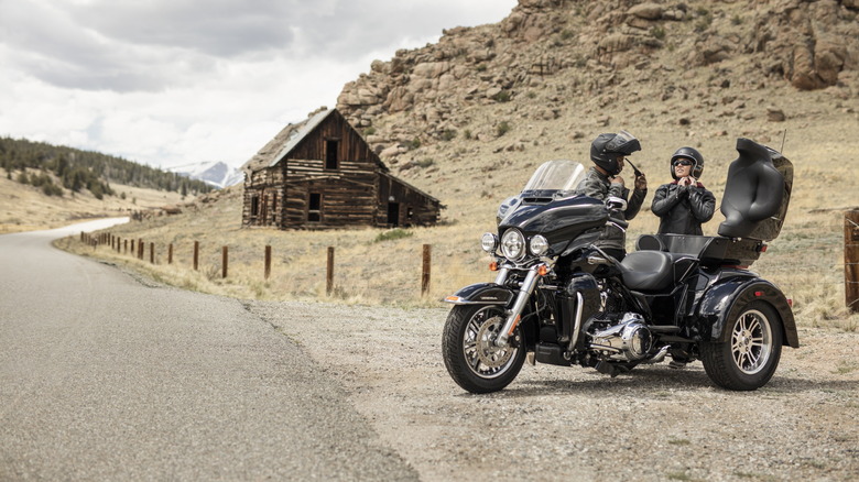 A rider in full gear fastening his helmet while sitting on a Tri Glide Ultra from 2019
