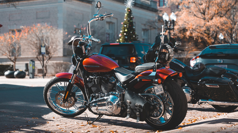 A red Harley-Davidson parked on the side of a town road in the middle of the day