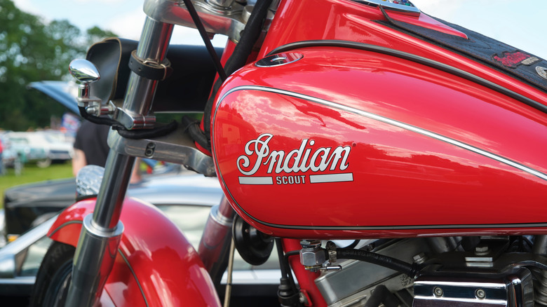 A close-up of a red Indian Scout motorcycle tank with the Indian badge on display