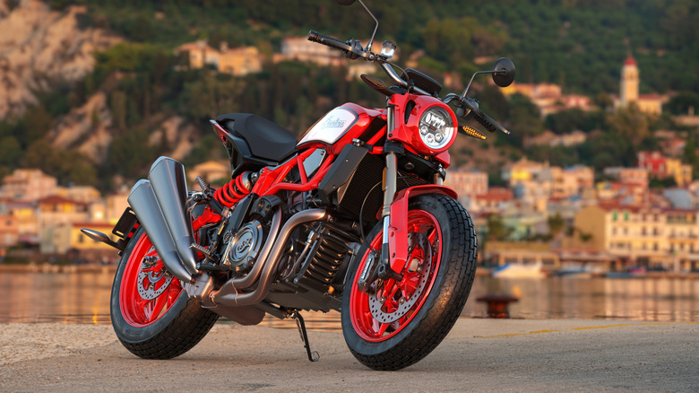 A Indian FTR 1200S parked on the street during the day with a town behind it