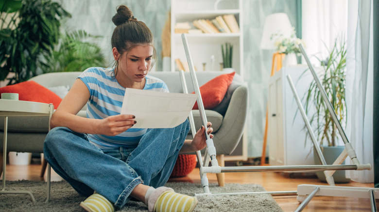 Woman reading instructions while assembling furniture