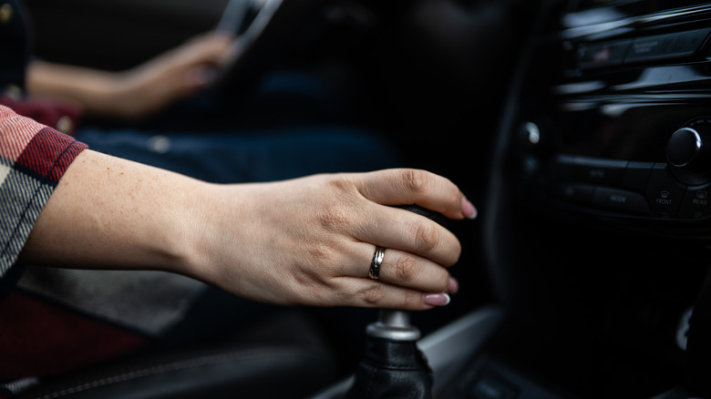 Close-up of hand resting on manual transmission shift knob, view from passenger seat