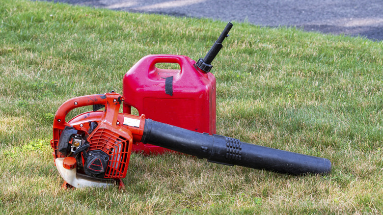 Orange gas-powered leaf blower on grass with gas container