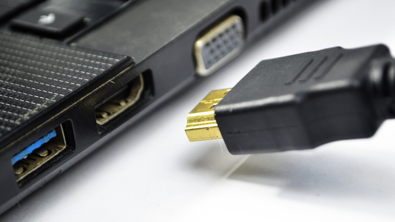 An HDMI cable being plugged into a laptop.
