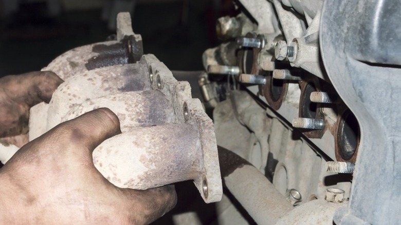 mechanic pulling out exhaust manifold from engine