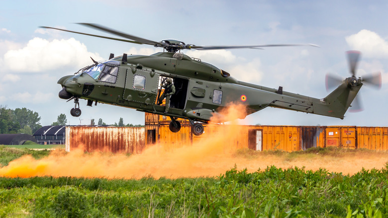 Military helicopter kicking up a dust cloud as it lands