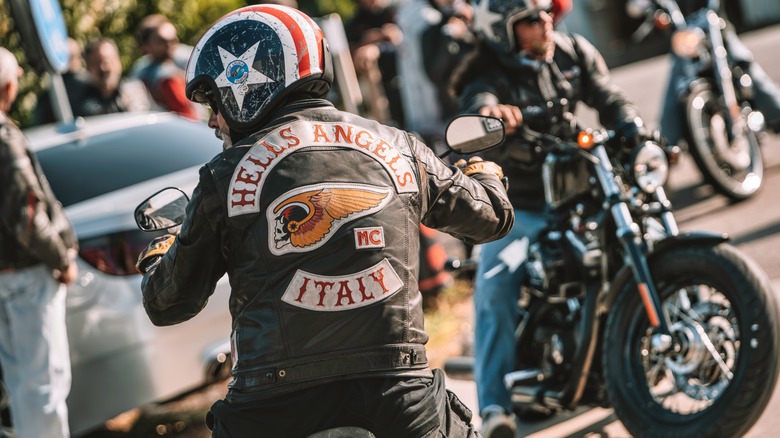 Hells angels rider on classic cruiser in leather jacket with patches