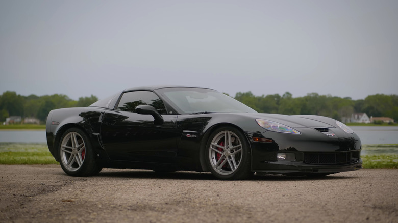 A black Chevrolet Corvette Z06 next to a lake, front 3/4 view