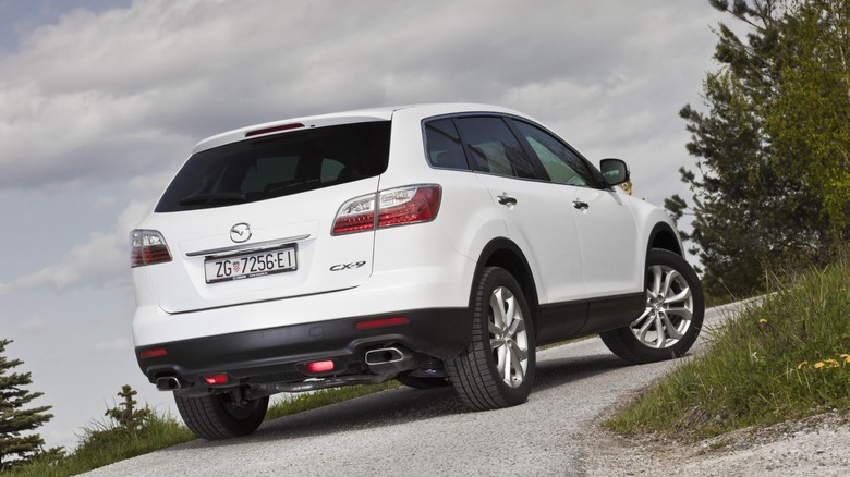 White Mazda CX-0 SUV going uphill a gravel road