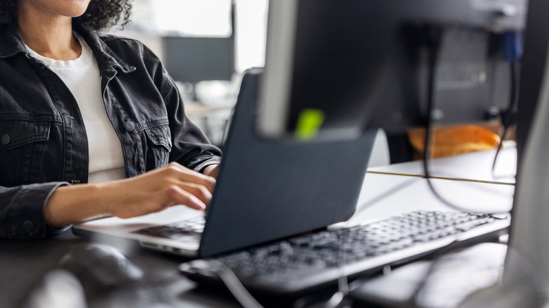 Woman in the office using laptop with monitor