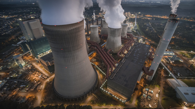 Aerial view of a coal-fired power station with large cooling towers. The picture is taken at night and the power station has its lights turned on.
