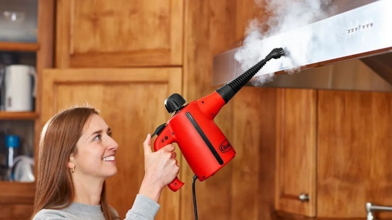 Woman using Grant's Handheld Steam Cleaner to clean hood vents