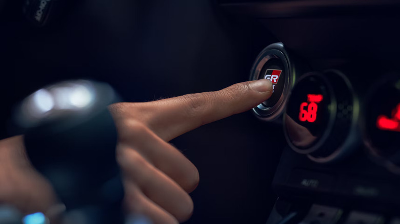 Close-up shot of a person pushing the start button in a Toyota GR86