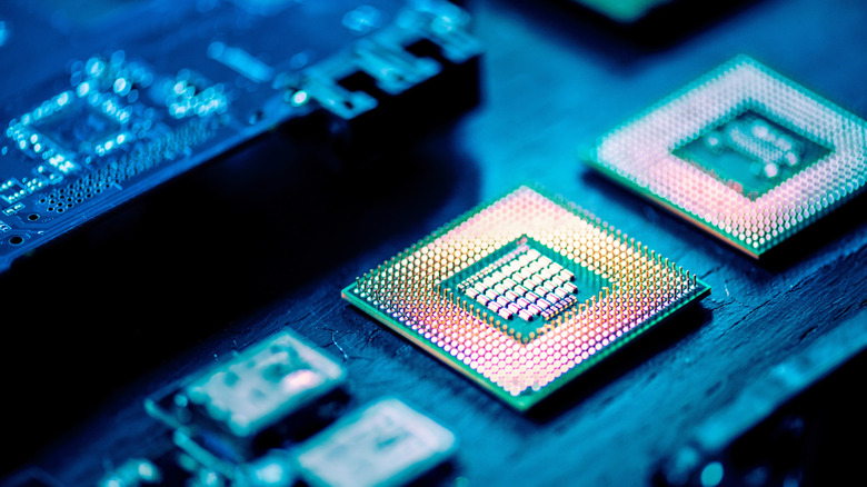 Two microchips, one near the centre shown more clearly on a blurred blue circuit background.