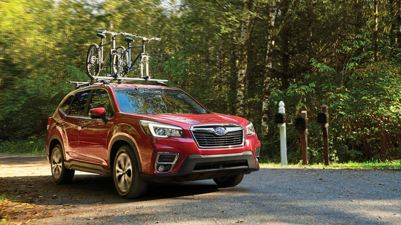 Red 2020 Subaru Forester driving on a rural road while carrying bicycles on roof rack