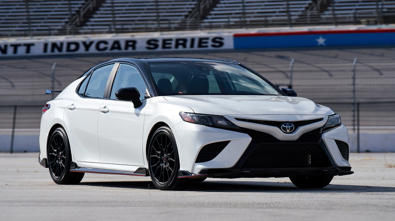 Front 3/4 view of white Toyota Camry TRD parked at race track.