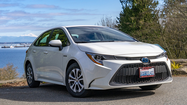 A 2021 Toyota Corolla hybrid in white parked at the edge of a lake in Washington state