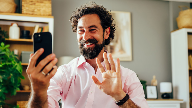 man waving while he makes a FaceTime call