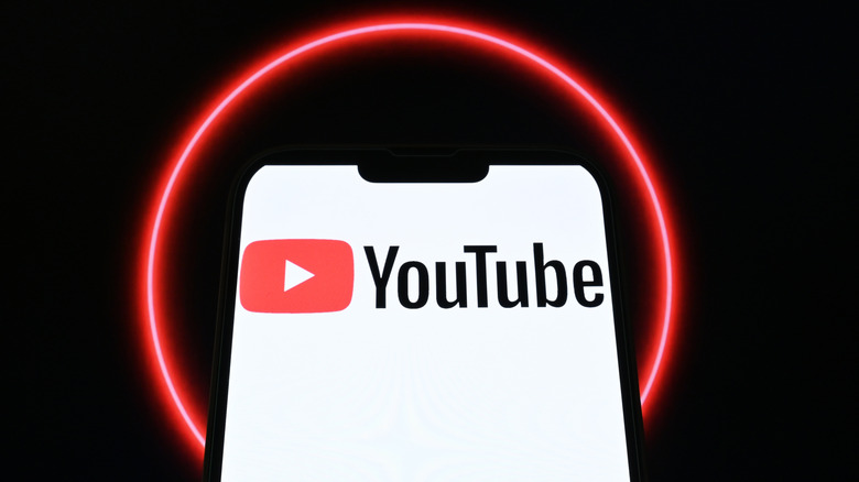 The YouTube logo on a smartphone screen circled by a red light.