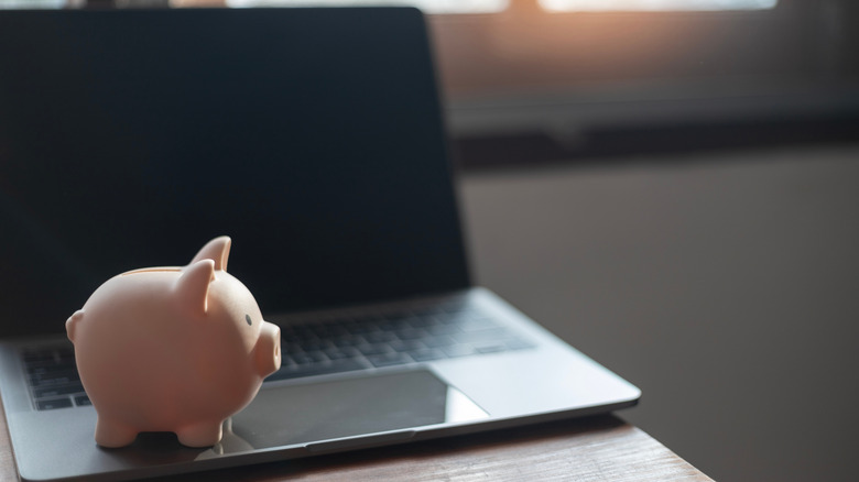 A Laptop With A Piggy Bank Sitting On It