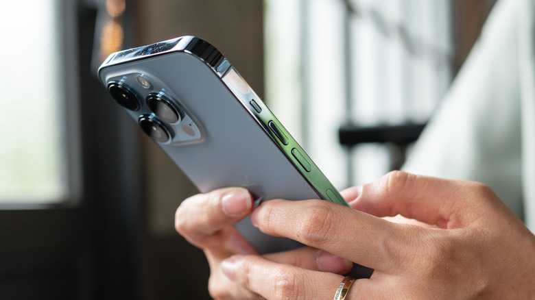 Person holding iPhone on tabletop