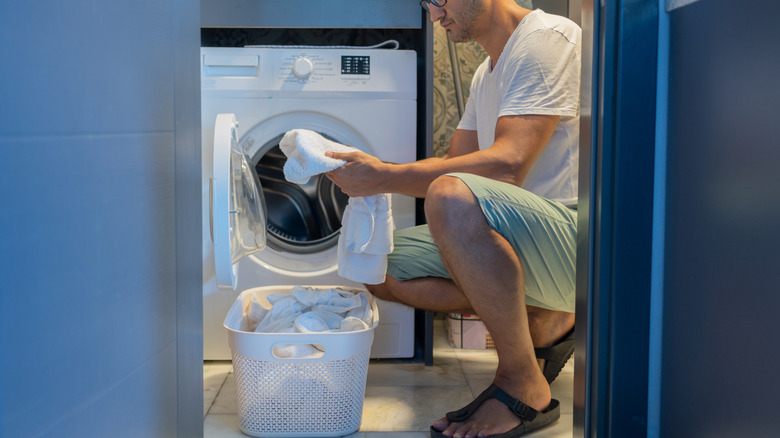 A person loading clothes into a washing machine