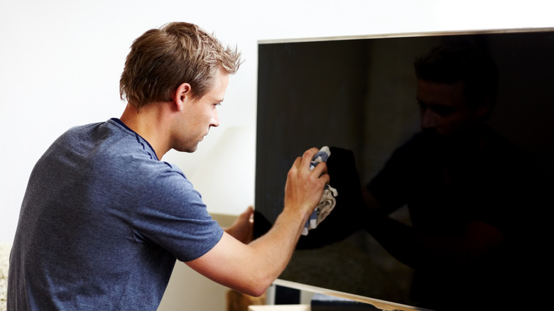man wiping tv screen