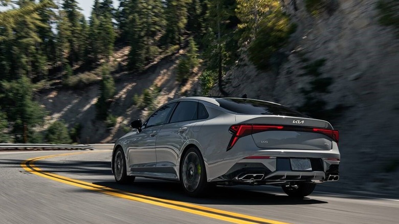 Rear-quarter shot of a driving 2026 Kia K6 in gray