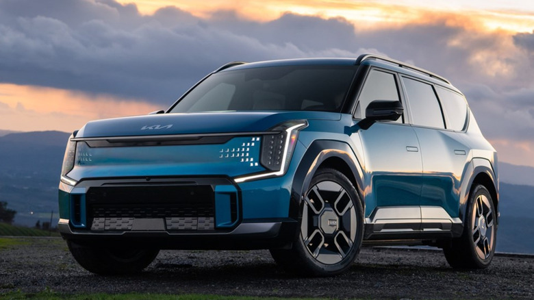 Front-quarter shot of a blue 2024 Kia EV9 against a scenic backdrop