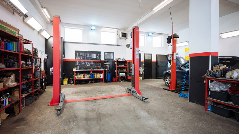 A red two-post car lift with no car on it in a clean garage workshop environment.