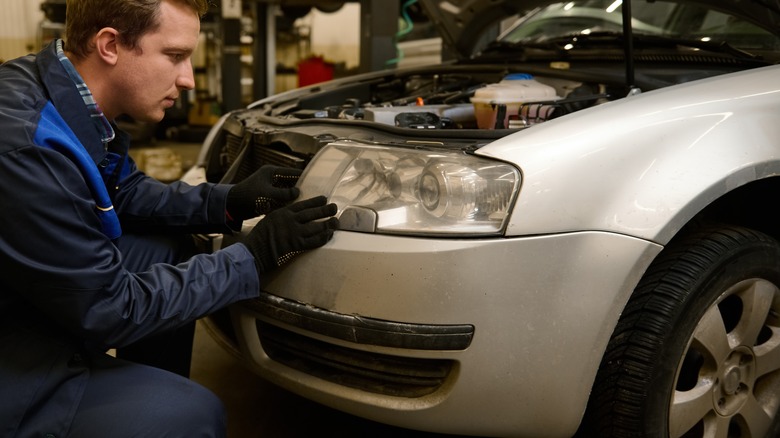 auto mechanic adjusts headlights