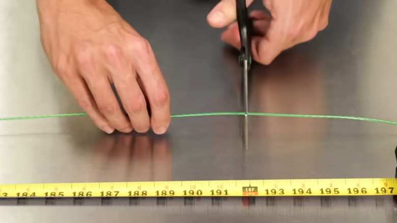 Hands cutting Ryobi String Trimmer wire