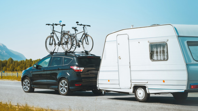 suv with trailer at the back and bikes on the roof