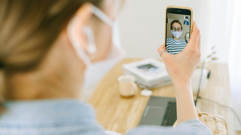 masked woman making a video call on an iPhone